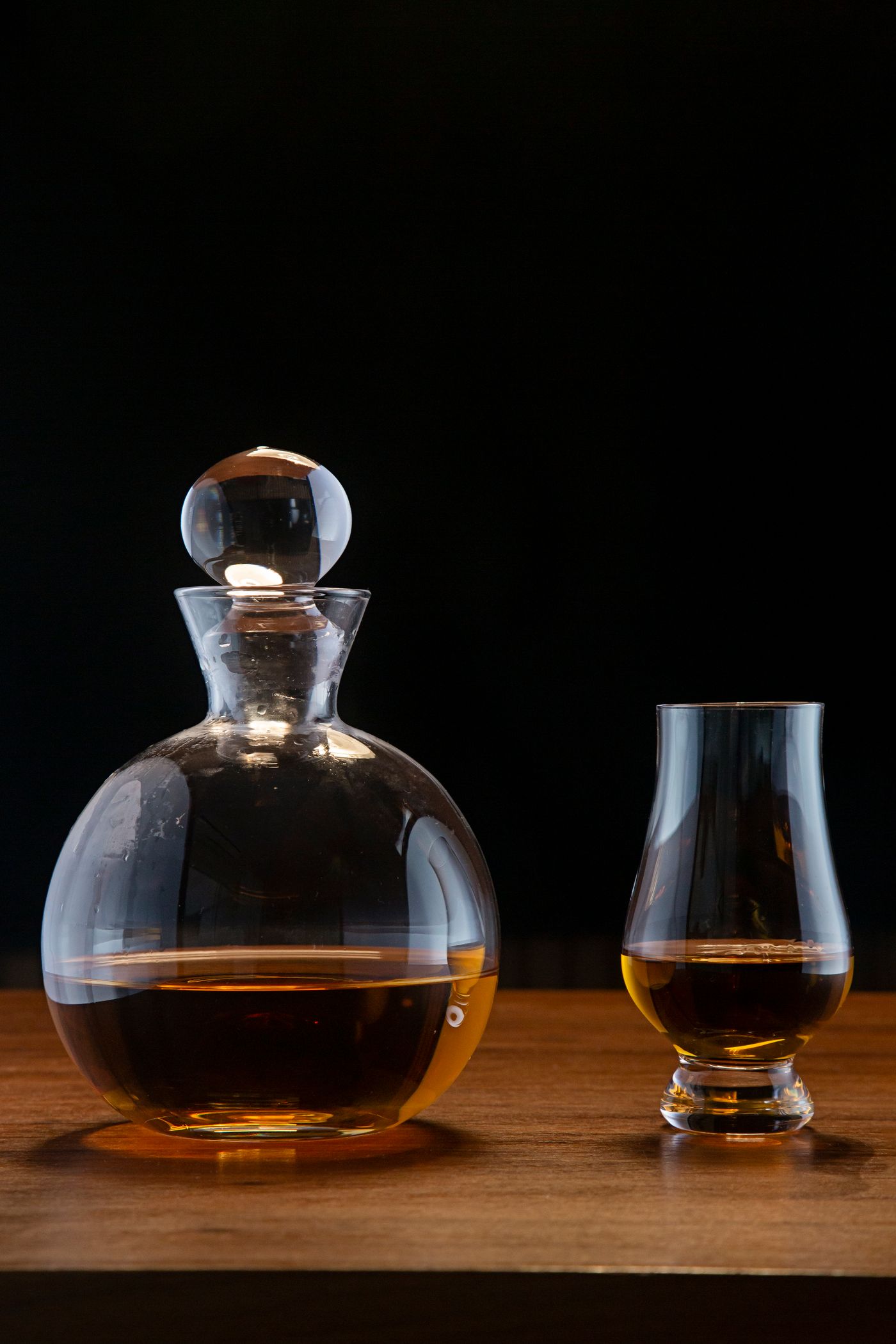 Kristallen karaf met een tulpvormig whiskyglas op een donkere achtergrond